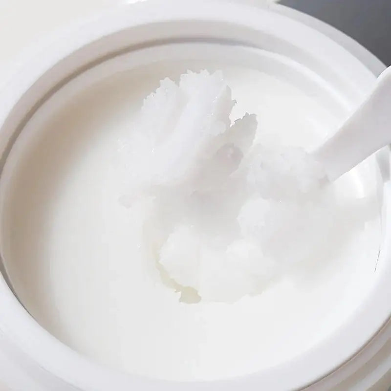 Witte pot met dikke witte reinigingsbalsem op spatel