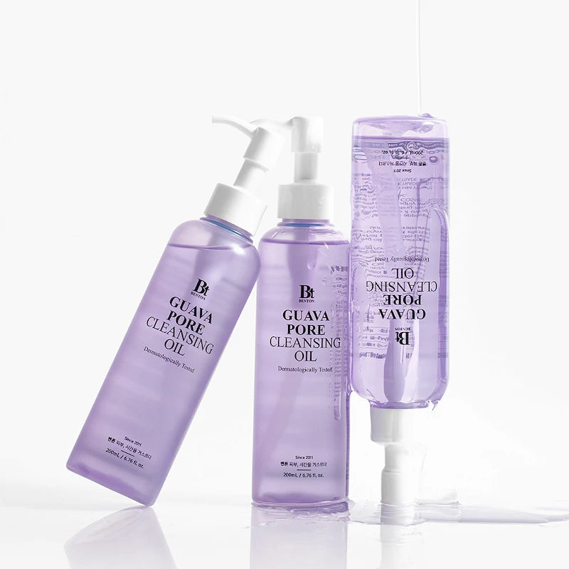 Opstapel (3 flessen): Drie flessen Benton Guava Pore Cleansing Oil 200ml gestapeld op witte achtergrond met paarse olie die uit de pomp stroomt