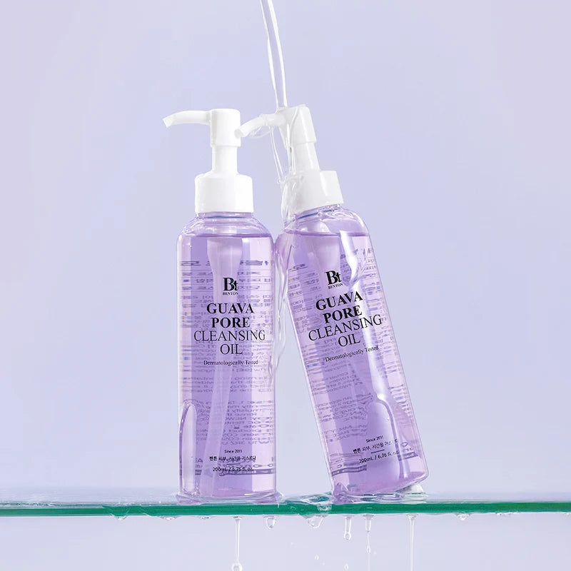 Water/textuur: Twee flessen Benton Guava Pore Cleansing Oil 200ml op glazen plank met waterdruppels en stromend water op lichtpaarse achtergrond
