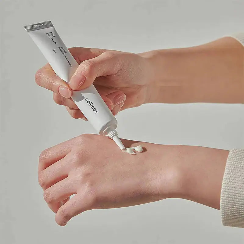 Celimax The Real Noni Ultimate Eye Cream Oogcrème tube met crème op hand, klaar voor aanbrengen
