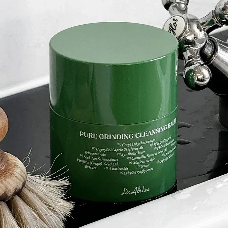 Groene Dr.Althea cleansing balm-pot op wastafel met waterdruppels.