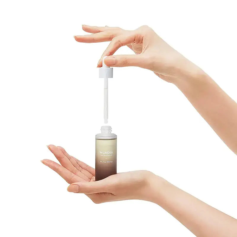 Haruharu WONDER Black Rice Facial Oil Gezichtsolieflacon met druppelpipet, handen die olie doseren