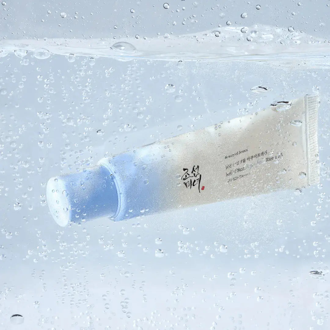 Zonnebrandcrème tube met waterdruppels, witte-blauwe verpakking in close-up.