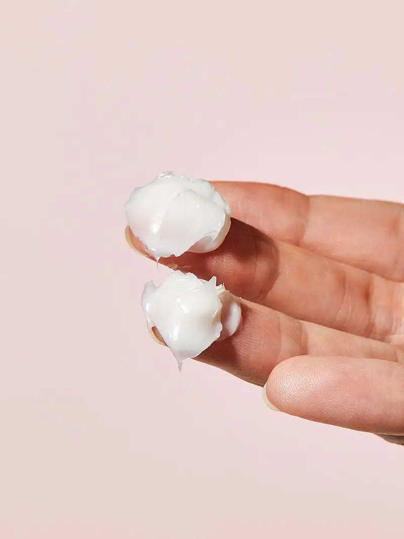 Ceramidecrème klodders op vinger, dikke witte crème met gladde textuur