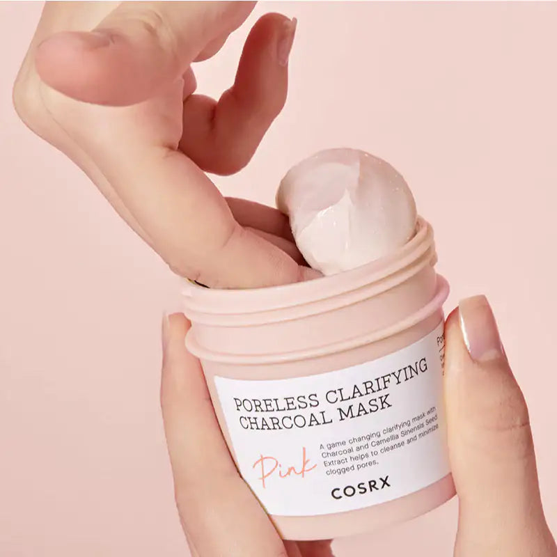 Handen houden Cosrx-koolstofmasker potje met wit etiket en roze tekst