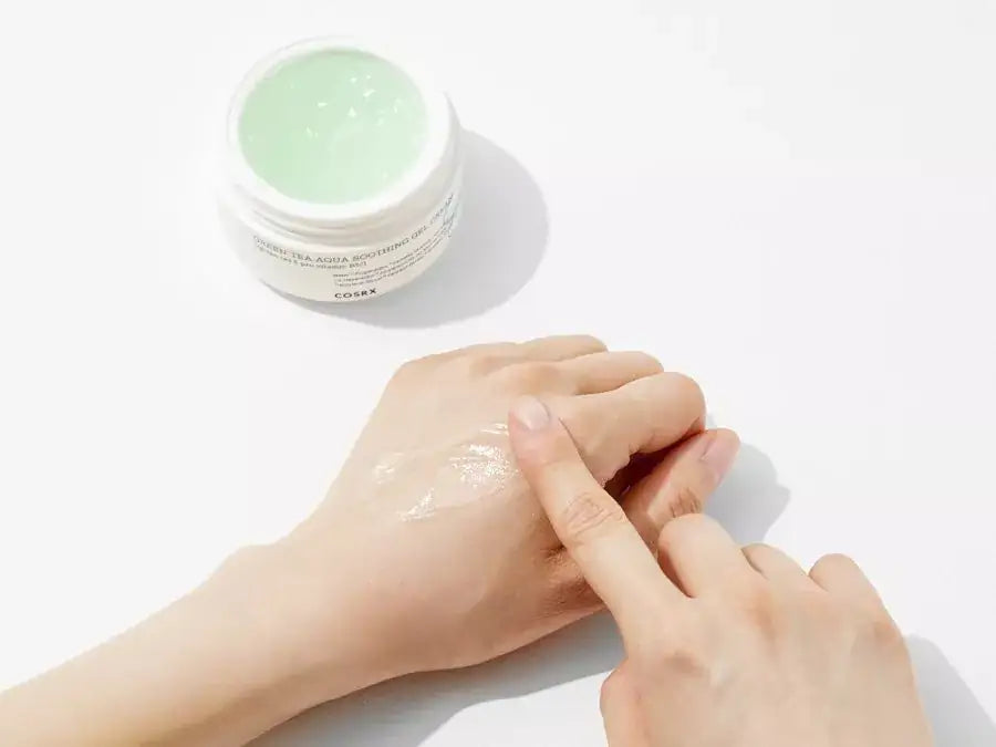 Hand die lichtgroene gelcrème smeert over de huid