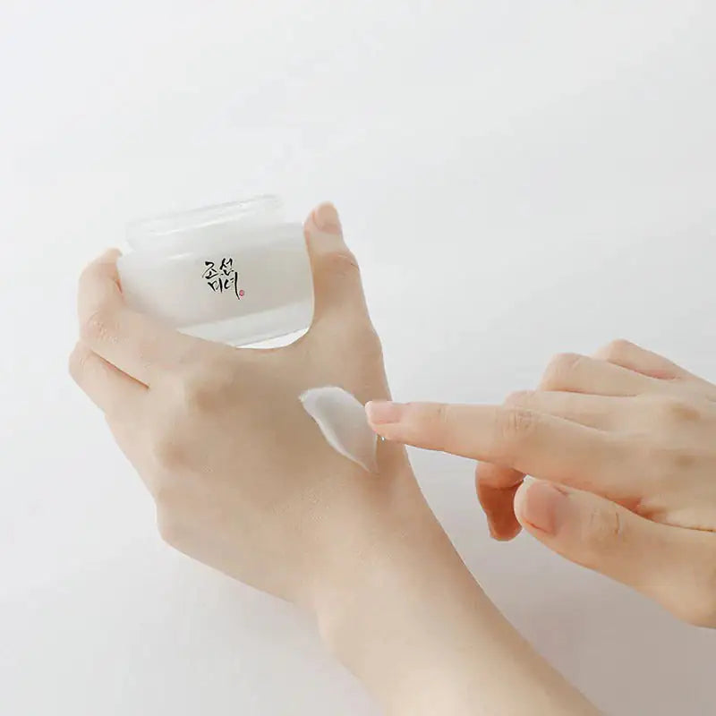 Dynasty cream pot met crème op schepje tussen handen
